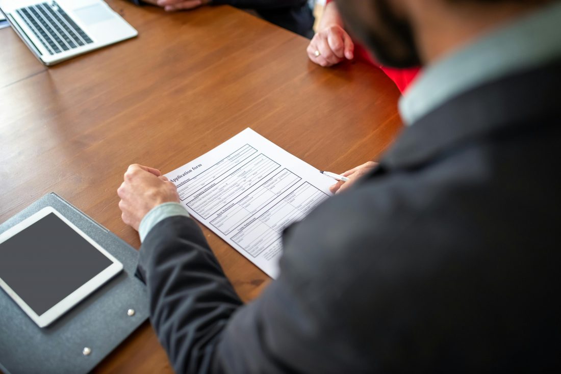 HR professional reviewing a job application form during a hiring interview, illustrating employee screening, candidate evaluation, and workplace background check process.